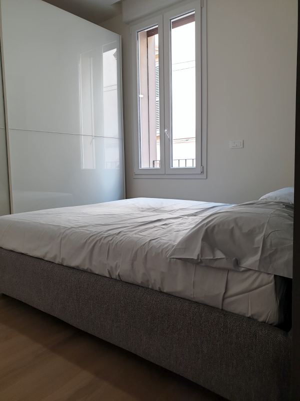 Double bed next to the window and the white sliding-door wardrobe